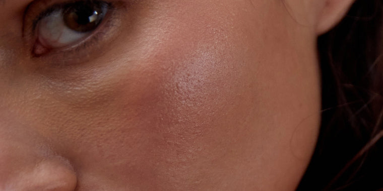 Eine Nahaufnahme des Gesichts einer Person, die den Bereich um die Wangenknochen und das Auge zeigt und eine glatte Hautstruktur und einen natürlichen, leicht taufrischen Teint hervorhebt.