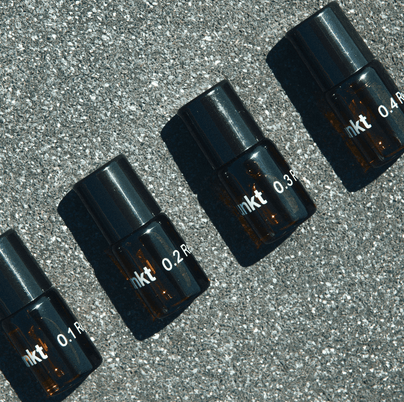 Vier kleine Braunglasflaschen mit schwarzen Deckeln, die mit 