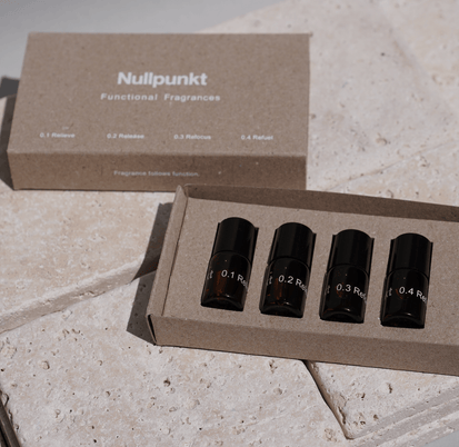 Das NULLPUNKT DISCOVERY SET von Nullpunkt besteht aus vier kleinen Braunglasflaschen - 0.1 Relieve, 0.2 Release, 0.3 Refocus und 0.4 Refuel - in einer Markenbox, die auf einer hellen Steinoberfläche präsentiert wird.