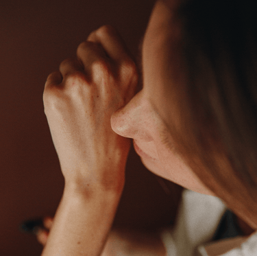 Eine Nahaufnahme von Gesicht und Hand einer Person, wobei die Knöchel und die Nase hervorgehoben werden, mit warmer Beleuchtung. Das Bild zeigt den Nullpunkt GRADE 0.2 RELEASE von Nullpunkt. Die Person scheint in Gedanken versunken zu sein, ihre Haut und ihr braunes Haar werden sanft beleuchtet.