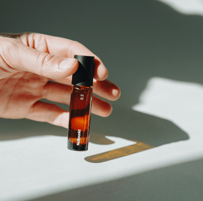 Eine Hand hält eine kleine Braunglasflasche mit einer schwarzen Kappe mit der Aufschrift 